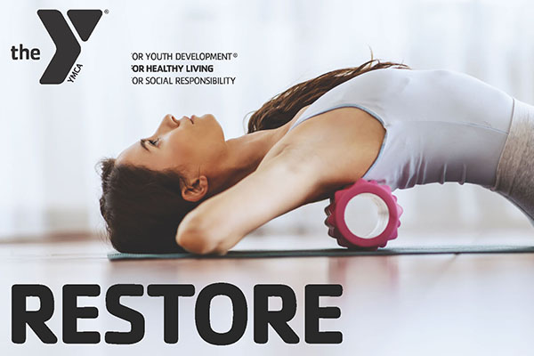 Woman using a pink foam roller on a yoga mat with YMCA logo in the corner.