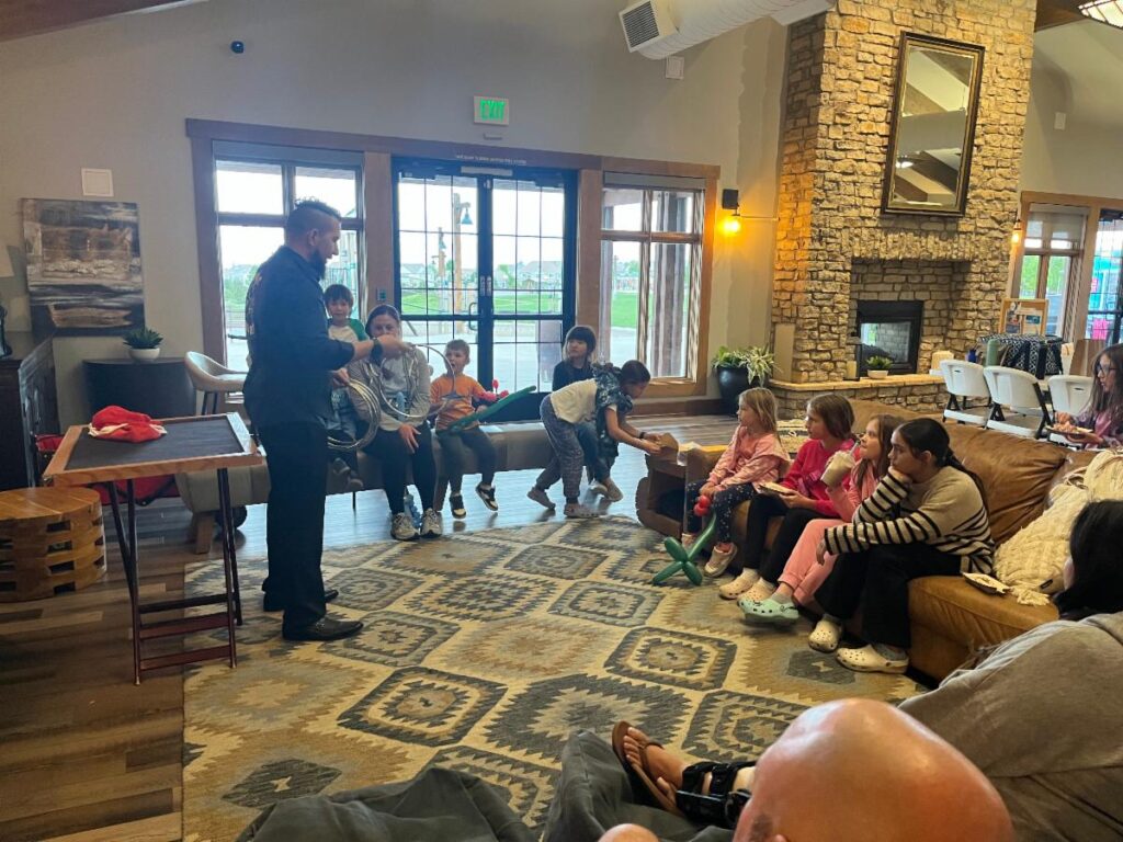 A person conducts an activity with attentive children in a cozy, rustic room.