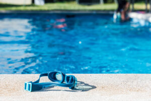 blue swim goggles with pool water in the background