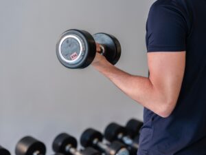Person lifting a dumbbell in a gym setting.