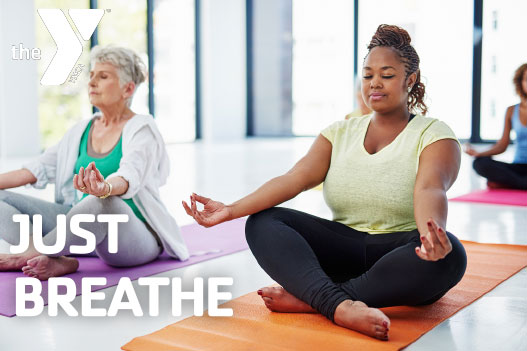 Two women sitting in a relaxed pose during yoga class.