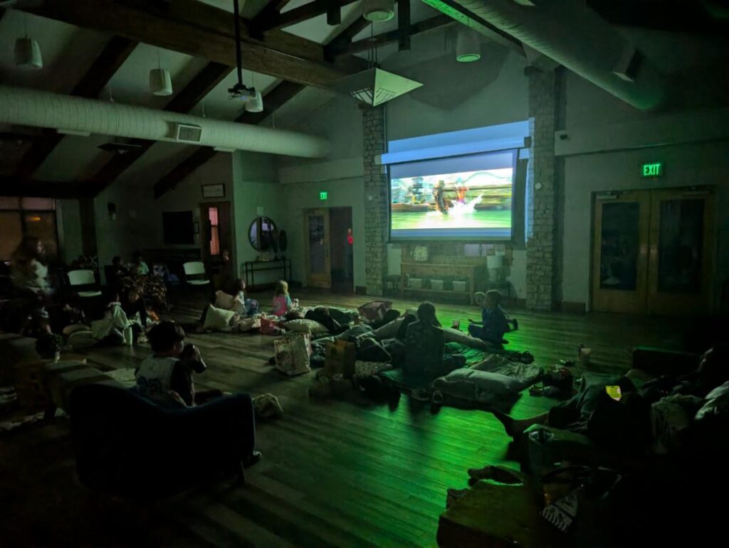 Photo of a group of families watching Zootopia 2 in a darkend room.