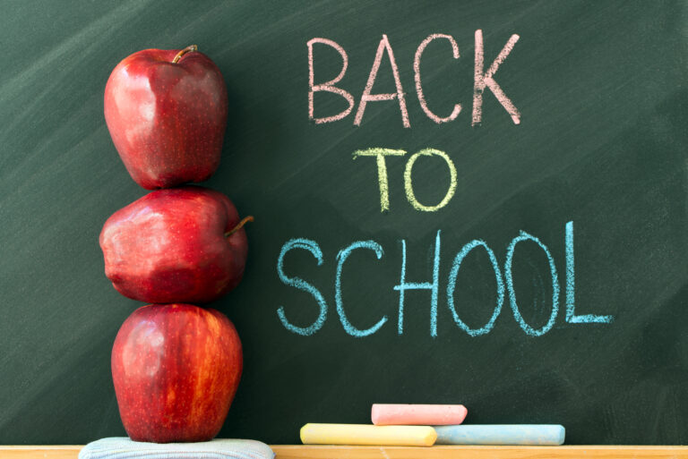 Colorful chalk words spelling Back to School with a stack of three red apples.