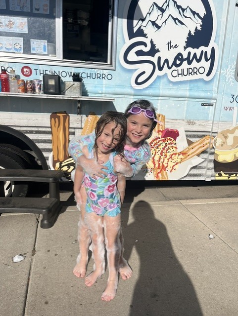 adult and child posing in fornt of ice cream food truck