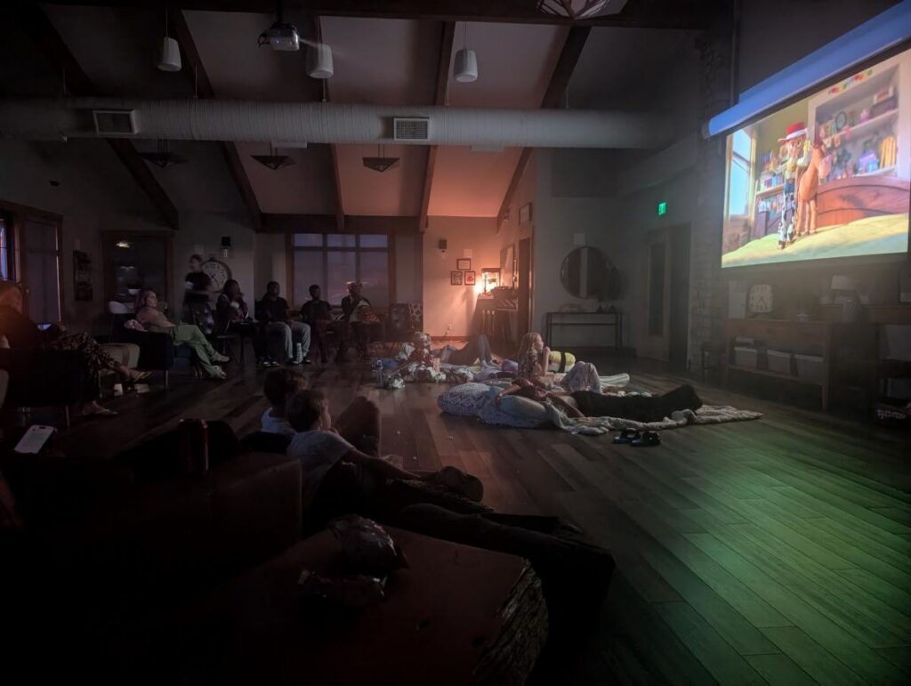 Families in a darkend cluhouse watching Toy Story 5.